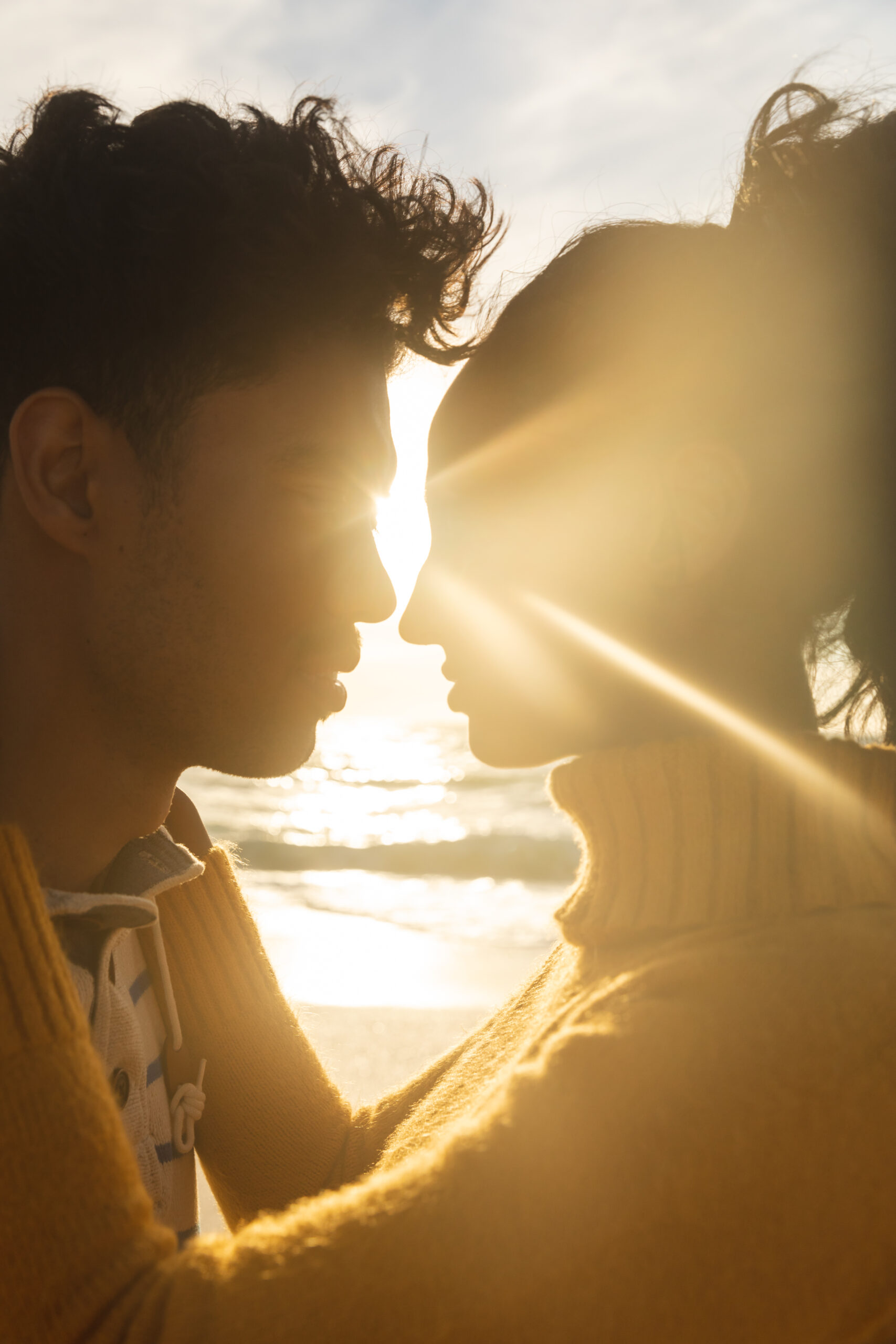 Back lit biracial couple face to face romancing at beach during sunset. lifestyle, love and weekend.