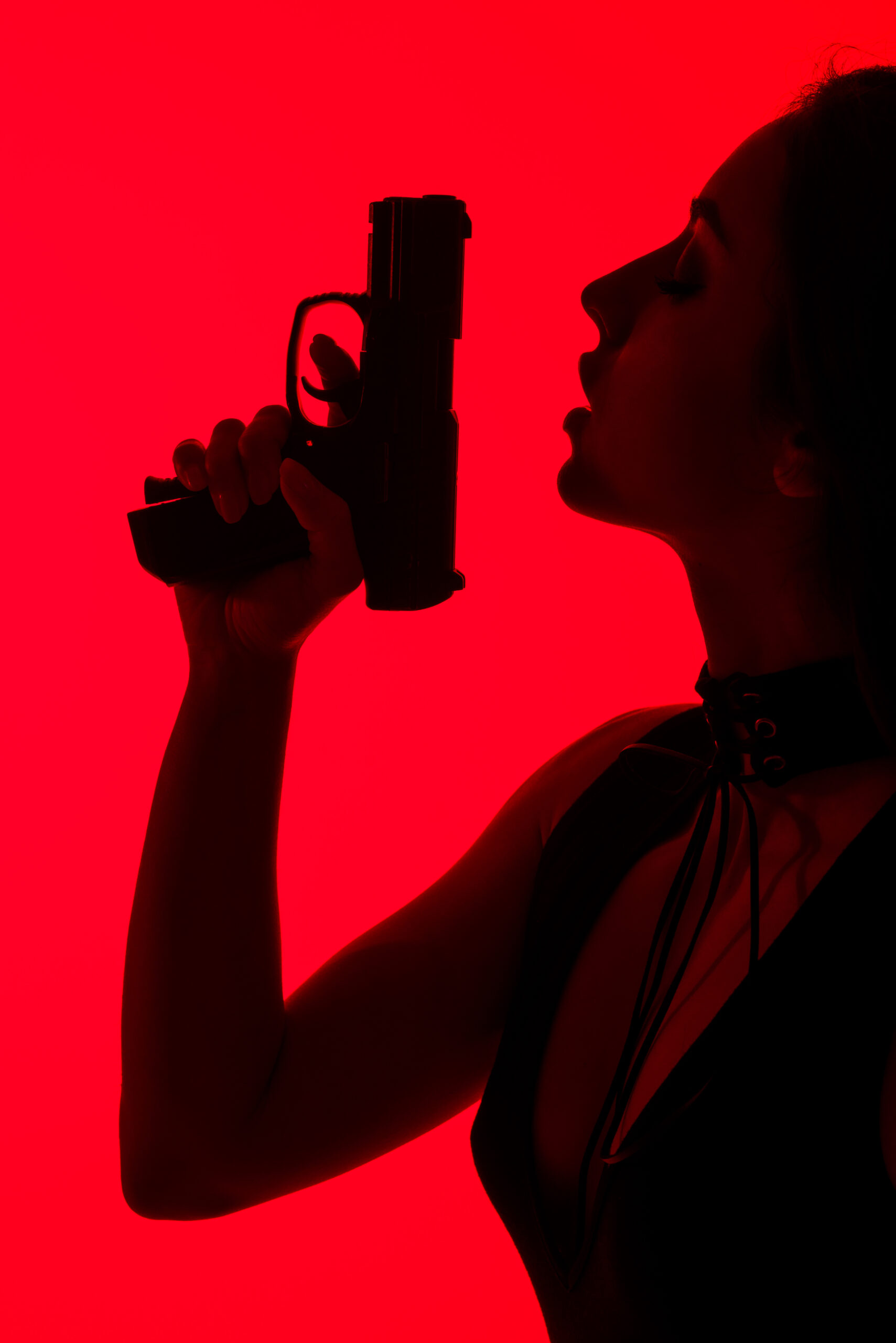 silhouette of seductive criminal woman holding gun isolated on red